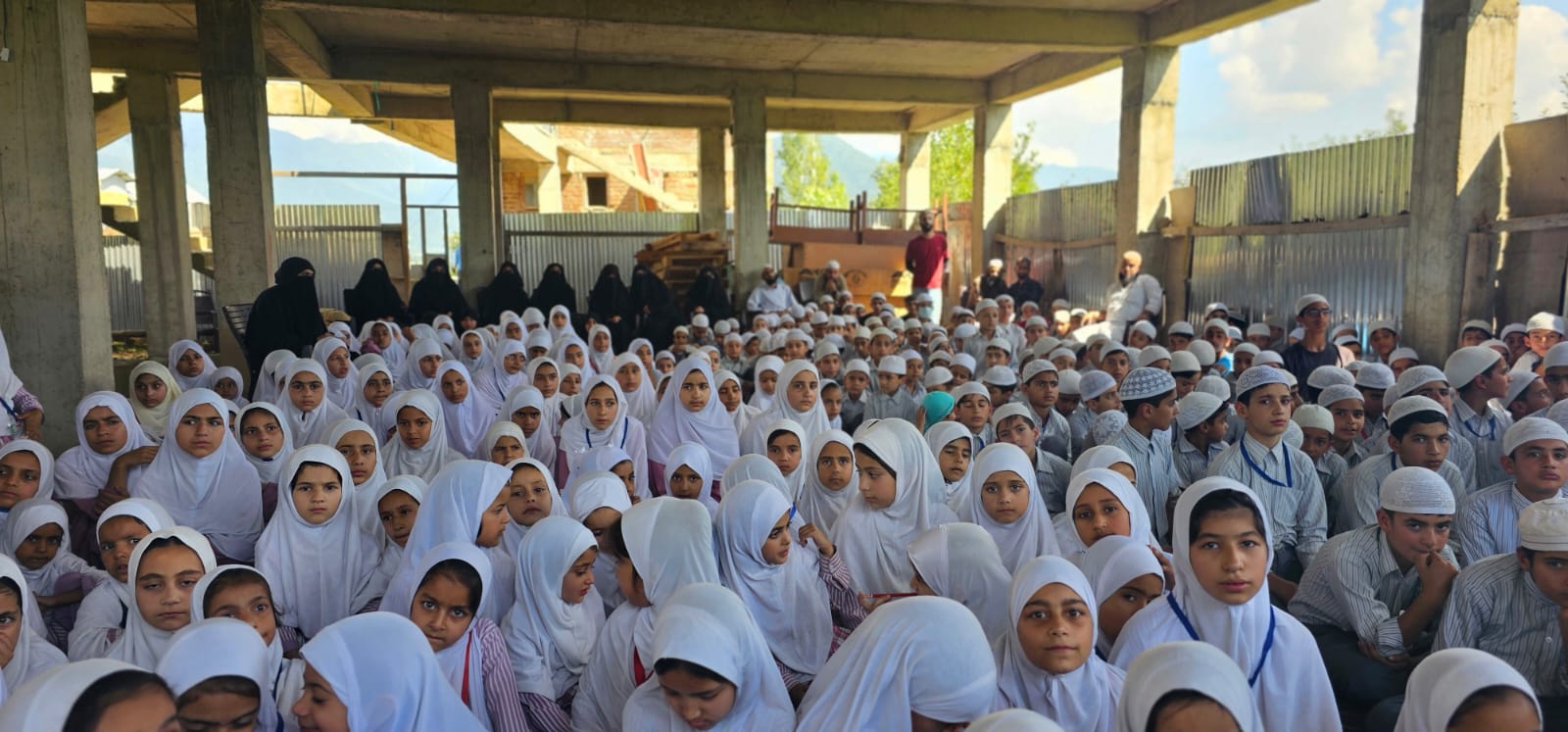 The whole school seated for assembly in the covered hall.